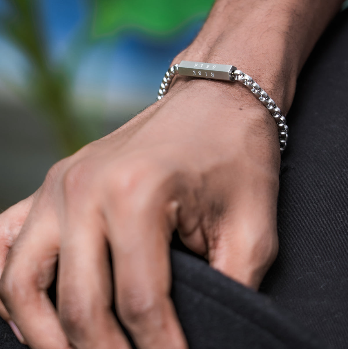 Close-up of a hand wearing a silver bracelet with a blurred background