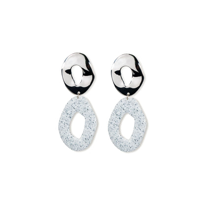 Pair of silver earrings with white speckled drops on a white background