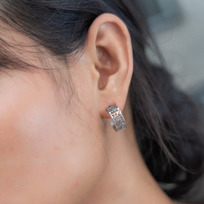 Close-up of an ear wearing a silver hoop earring with a blurred background