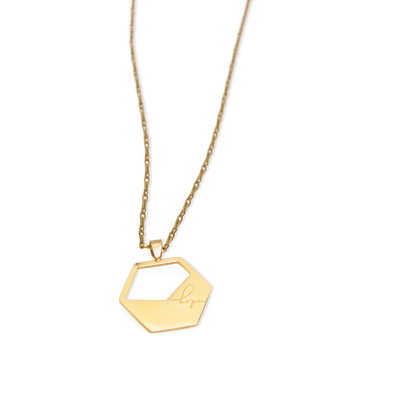 Gold necklace with a geometric pendant on a white background