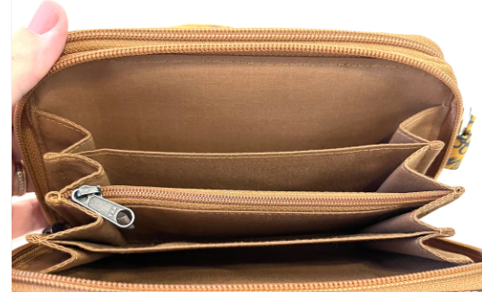 Brown leather wallet with multiple compartments and a zipper, held open by a hand.