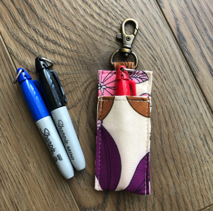 Fabric keychain pouch with pens on a wooden surface