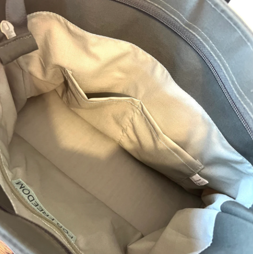 Close-up of a beige pillow inside a gray bag with a visible brand label.