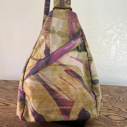Multicolored patterned sling bag on a wooden surface with a neutral background
