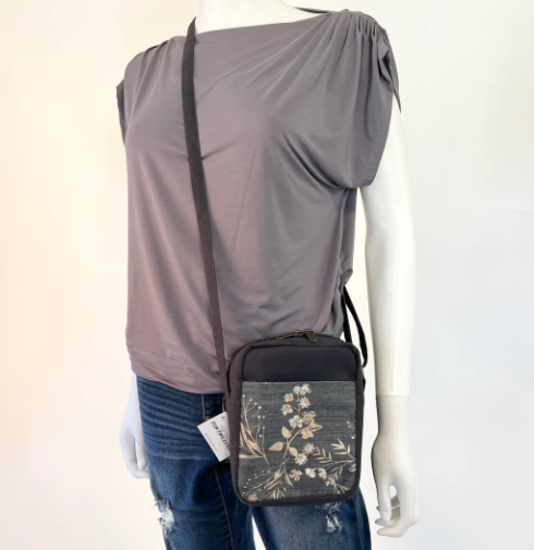 Mannequin wearing a gray top and blue jeans with a black crossbody bag featuring floral design.