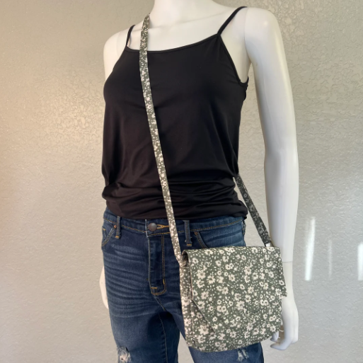 Mannequin wearing a black tank top and blue jeans with a floral crossbody bag on a neutral background