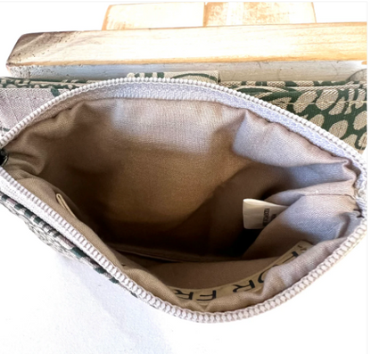 Close-up of a fabric pouch with a zipper, showing the interior and brand name.