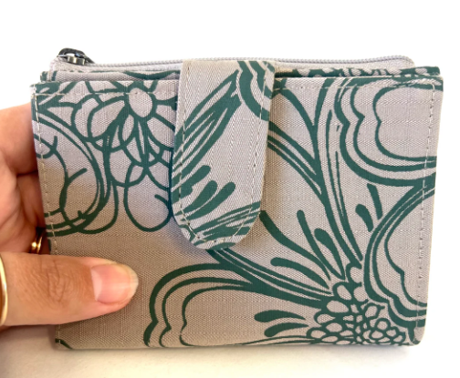 Fabric pouch with green floral pattern held by a hand on a white background