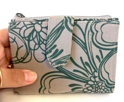 Fabric pouch with green floral pattern held by a hand on a white background