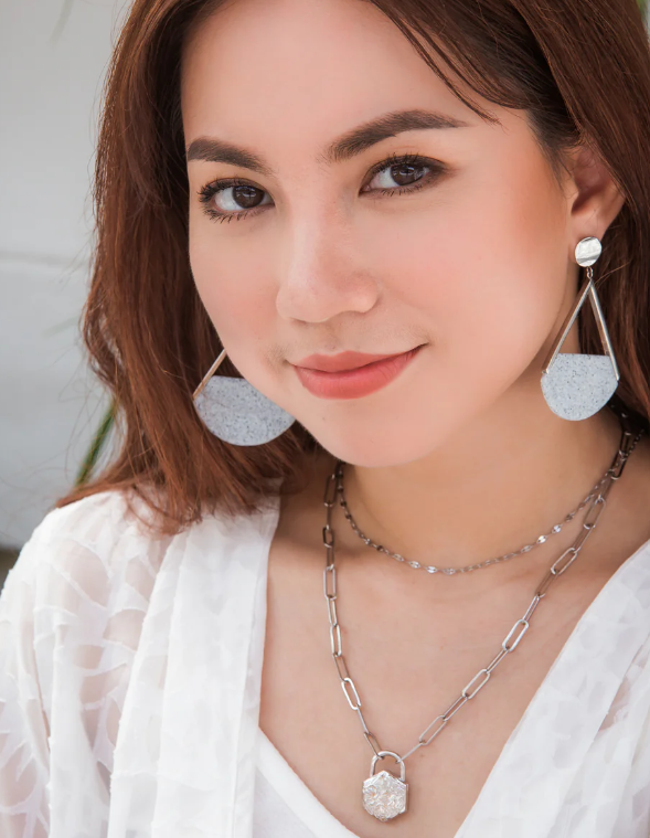Woman wearing silver earrings and necklace with a blurred background