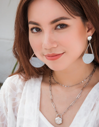 Woman wearing silver earrings and necklace with a blurred background