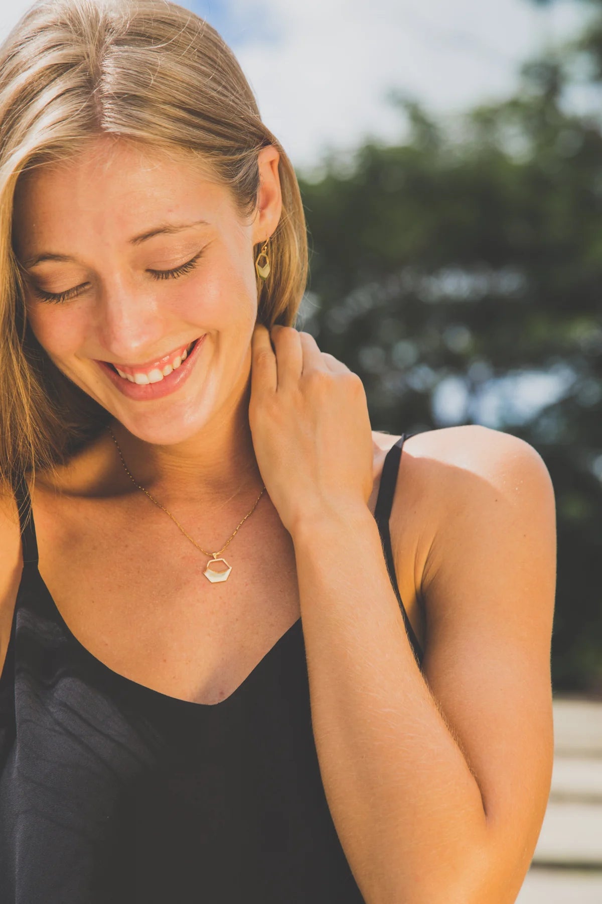 Woman wearing a necklace with a hexagon pendant outdoors