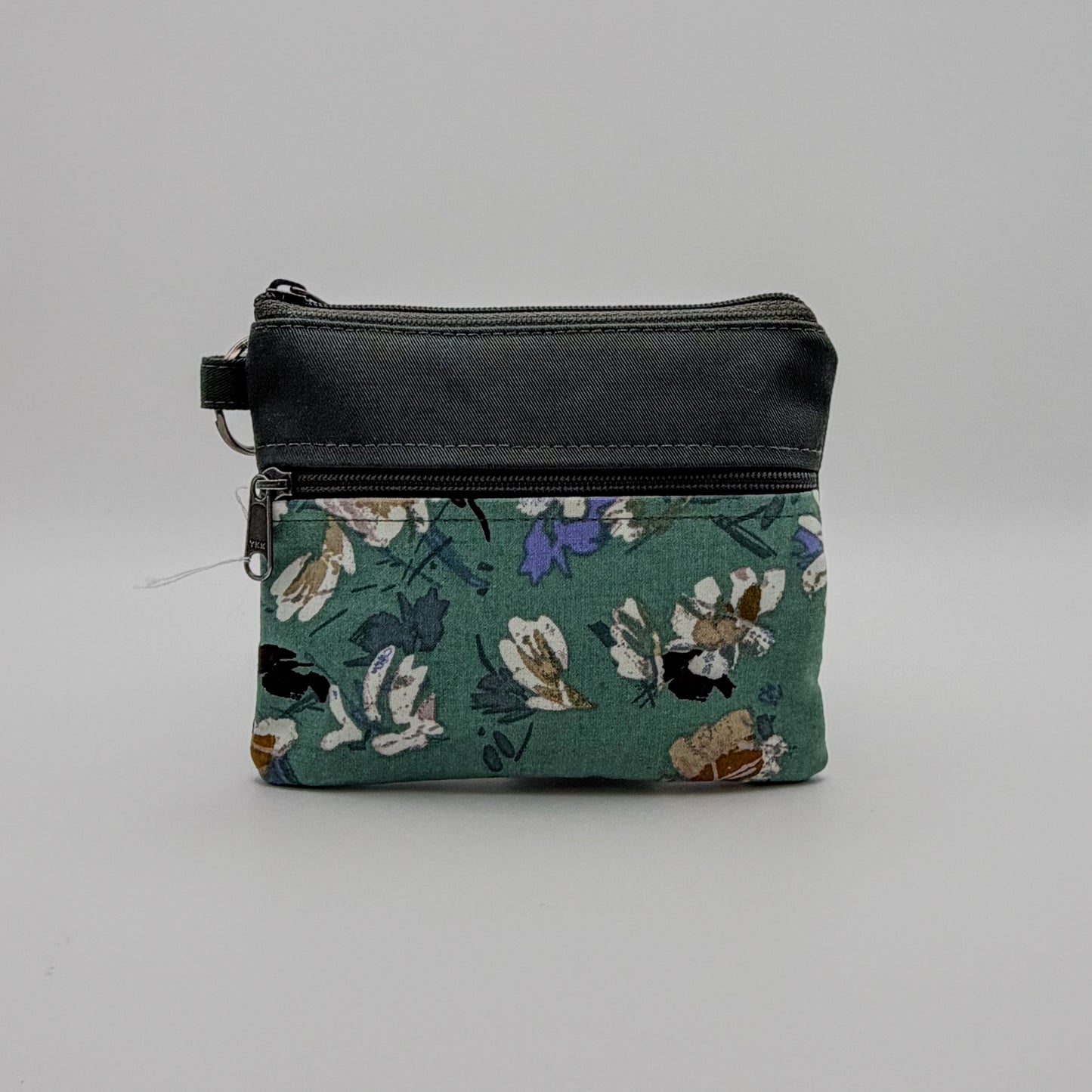 Floral-patterned pouch with a black zipper on a gray background