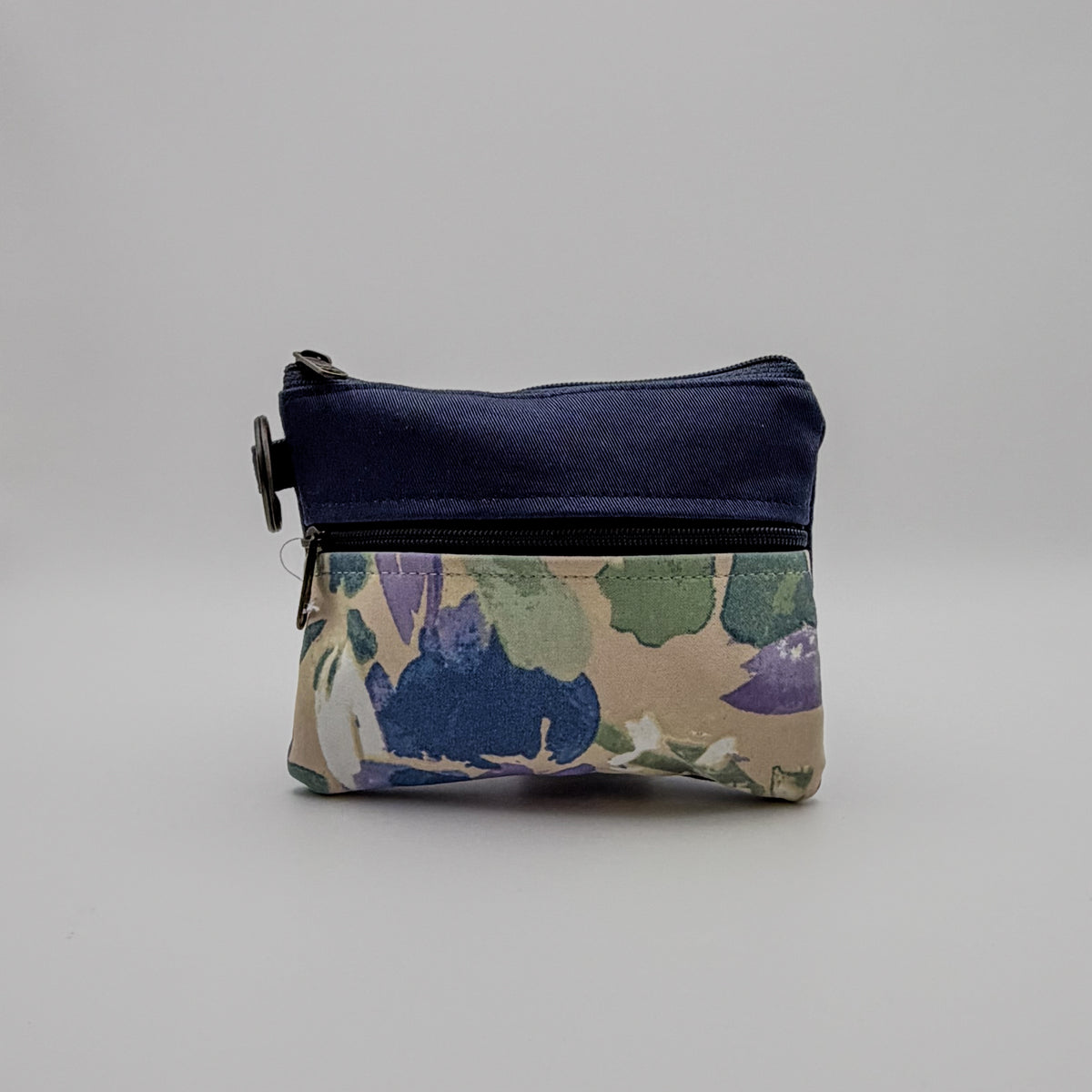 Floral-patterned pouch with a navy blue top section on a gray background