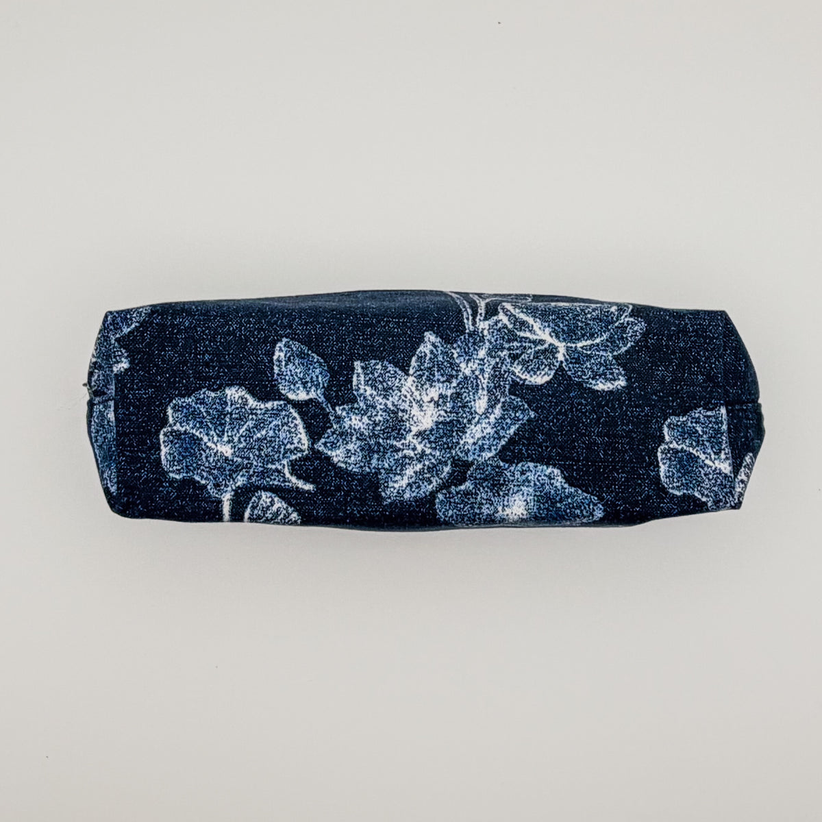 Navy pencil case with white floral pattern on a light gray background