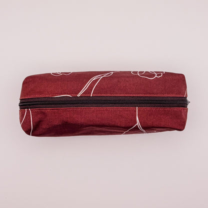 Red pouch with white floral patterns and a black zipper on a light pink background
