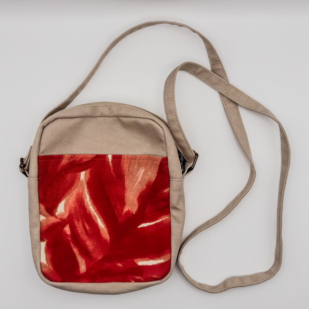 Crossbody bag with a red and beige design on a white background