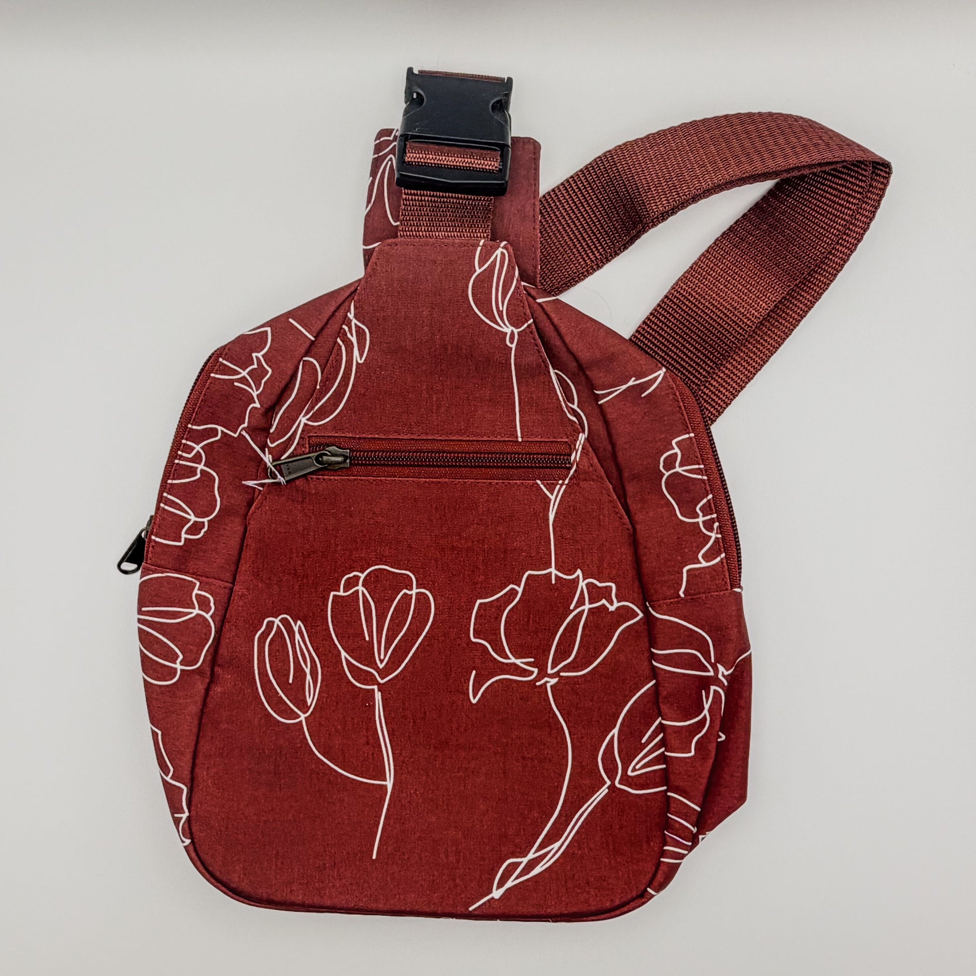 Red sling bag with floral patterns on a light gray background