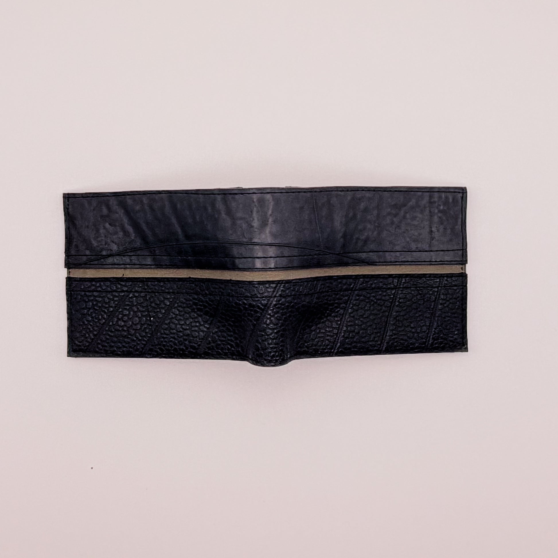 Black leather wallet with a zipper on a light beige background