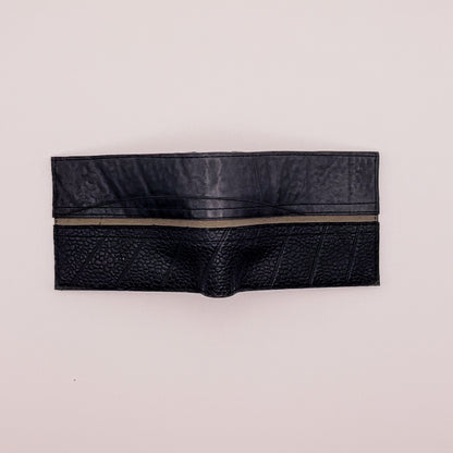 Black leather wallet with a zipper on a light beige background