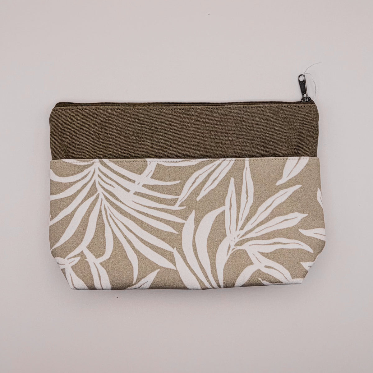 Fabric pouch with leaf pattern and brown zipper on a light gray background