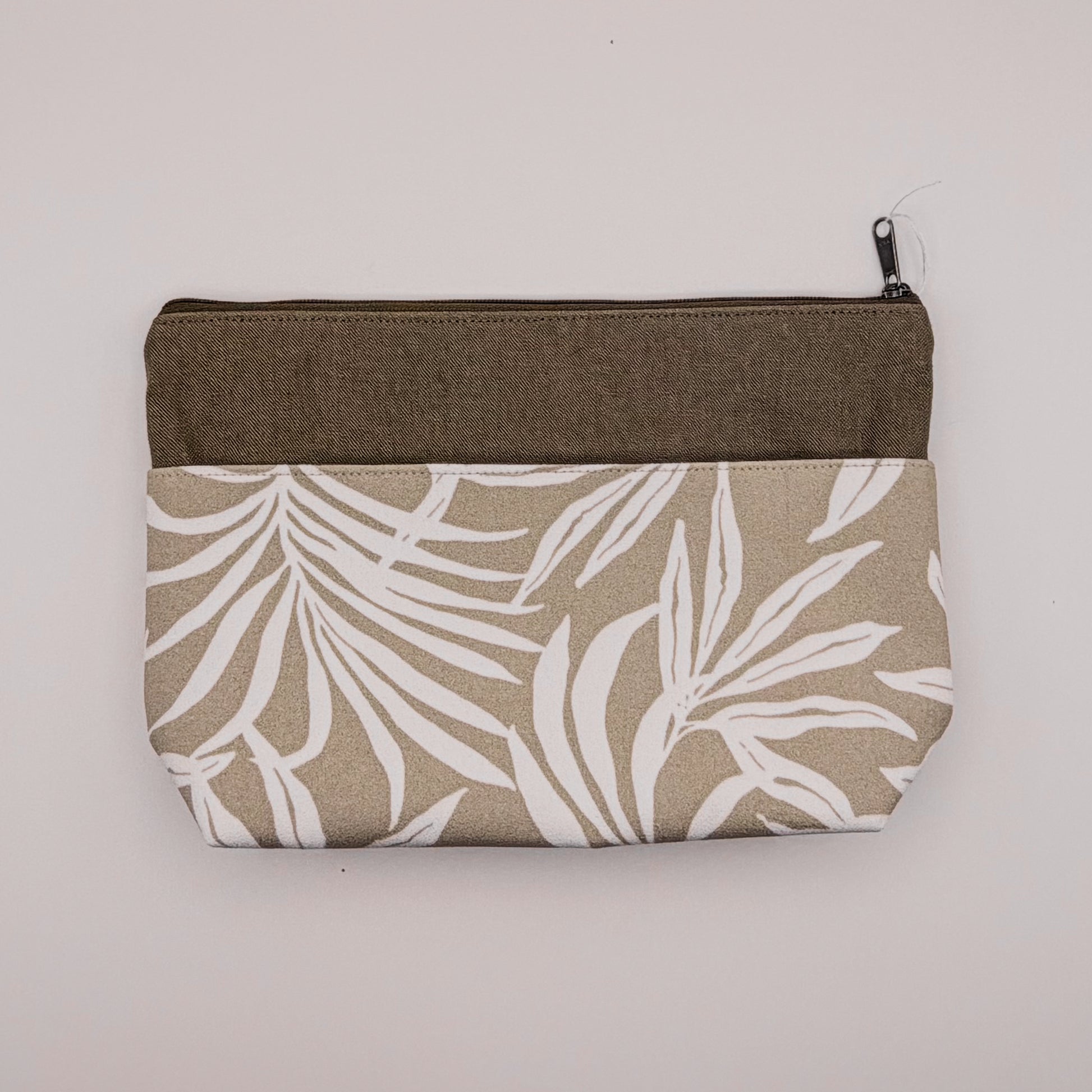 Fabric pouch with leaf pattern and brown zipper on a light gray background