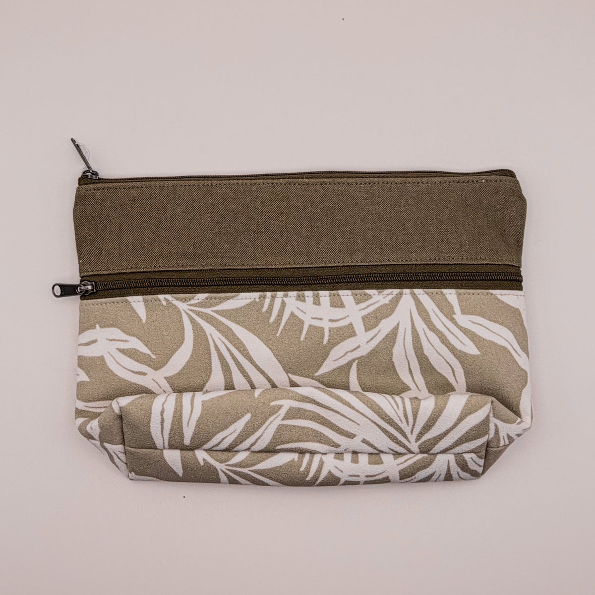 Fabric pouch with leaf pattern and olive green zipper on a light gray background
