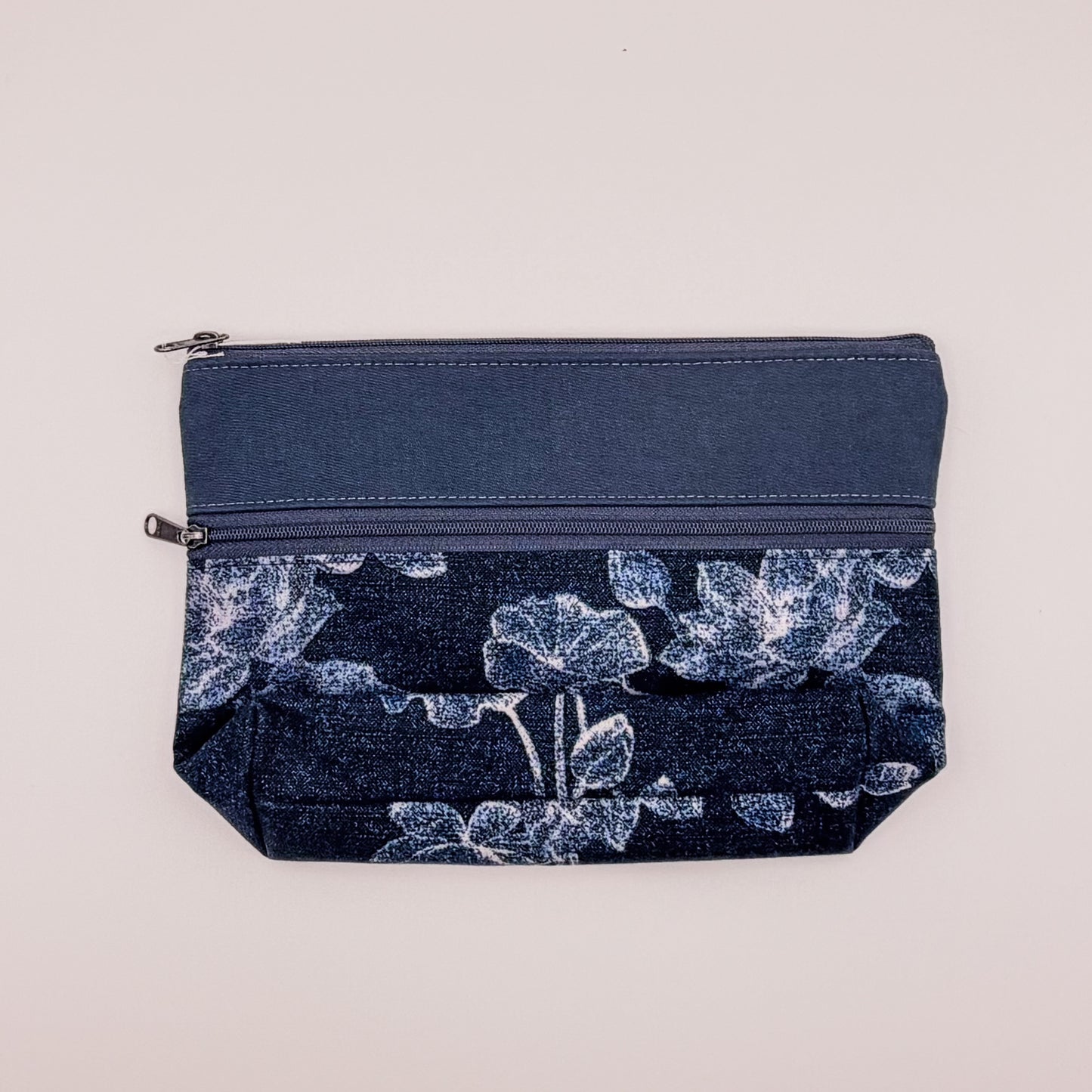 Navy blue pouch with floral pattern on a light gray background
