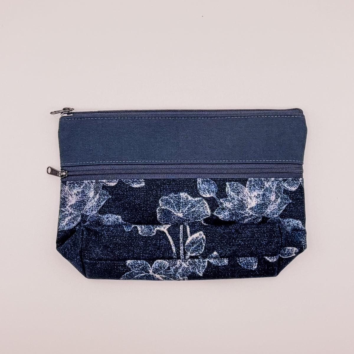 Navy blue pouch with floral pattern on a light gray background