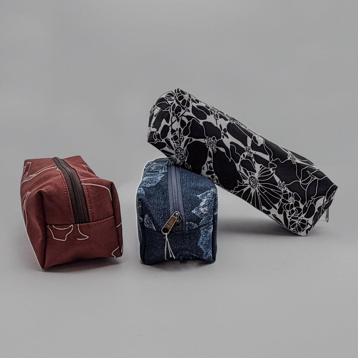 Three fabric pouches in different colors on a gray background