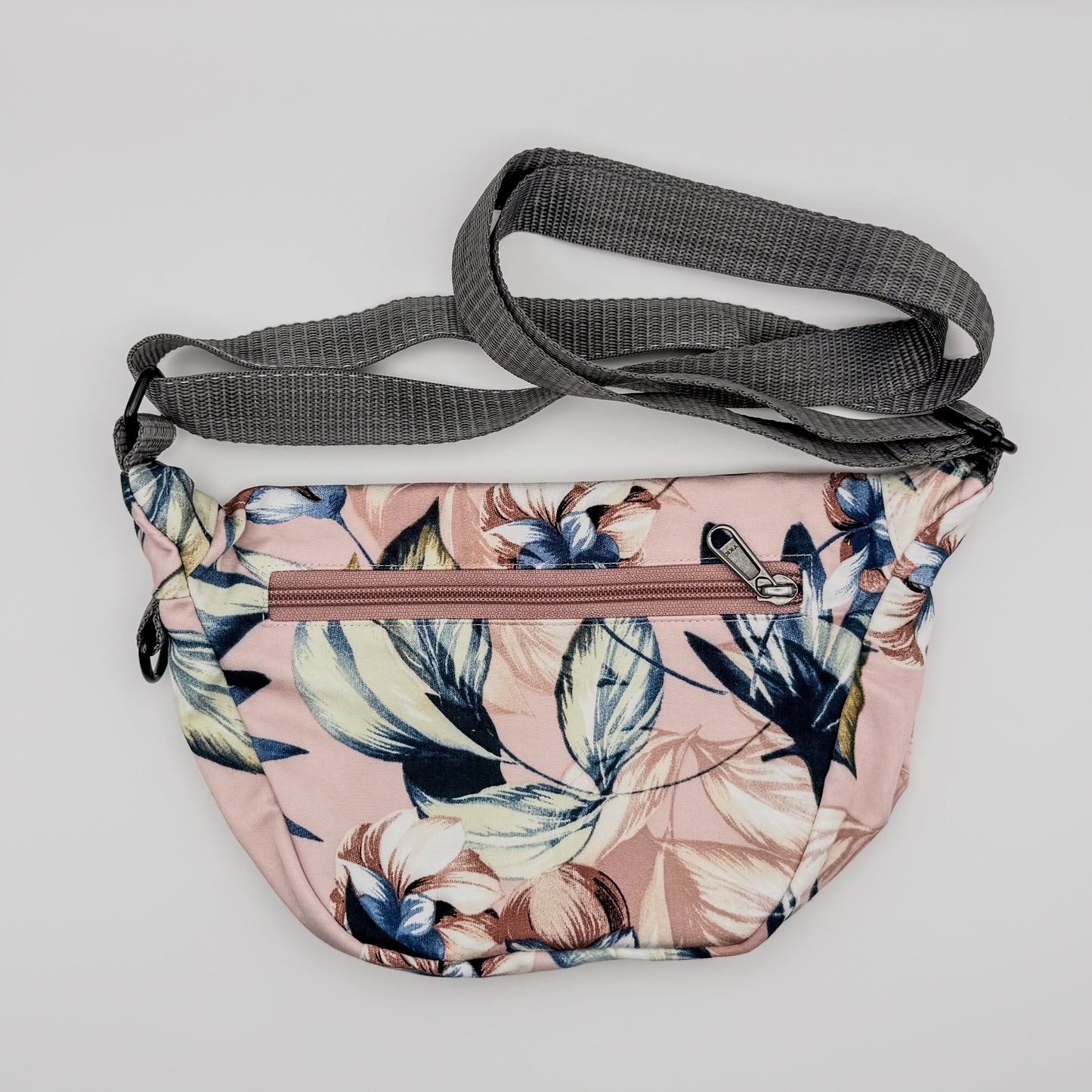 Floral-patterned crossbody bag with a gray strap on a light gray background