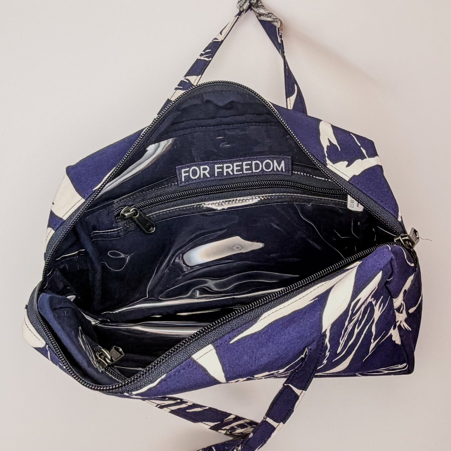 Navy blue bag with white floral pattern and 'For Freedom' text on a light gray background