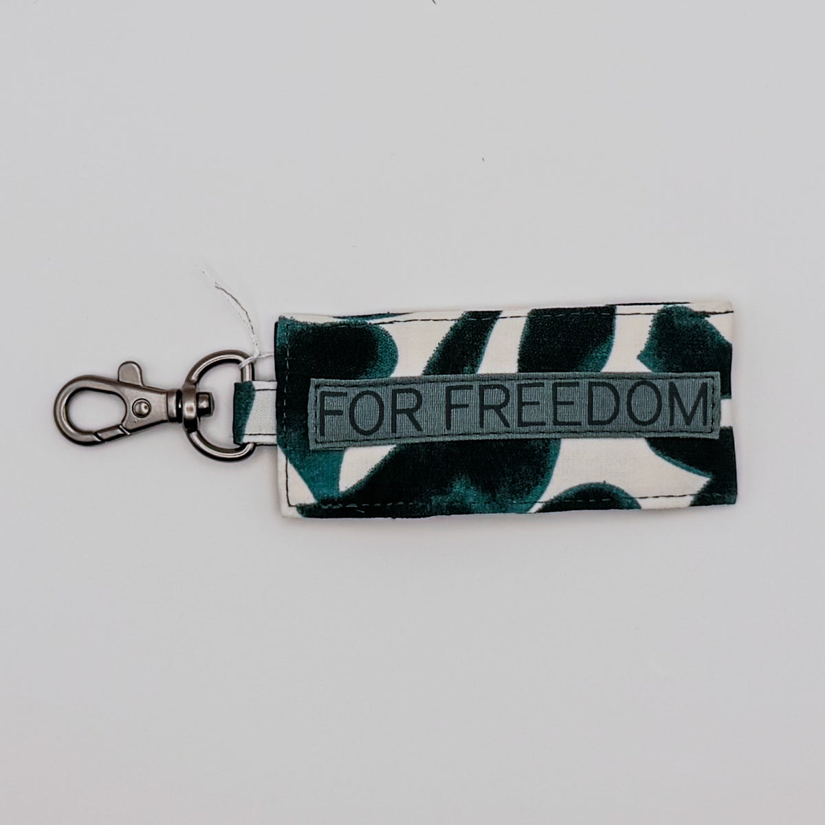 Keychain with leaf pattern and 'FOR FREEDOM' text on a light gray background