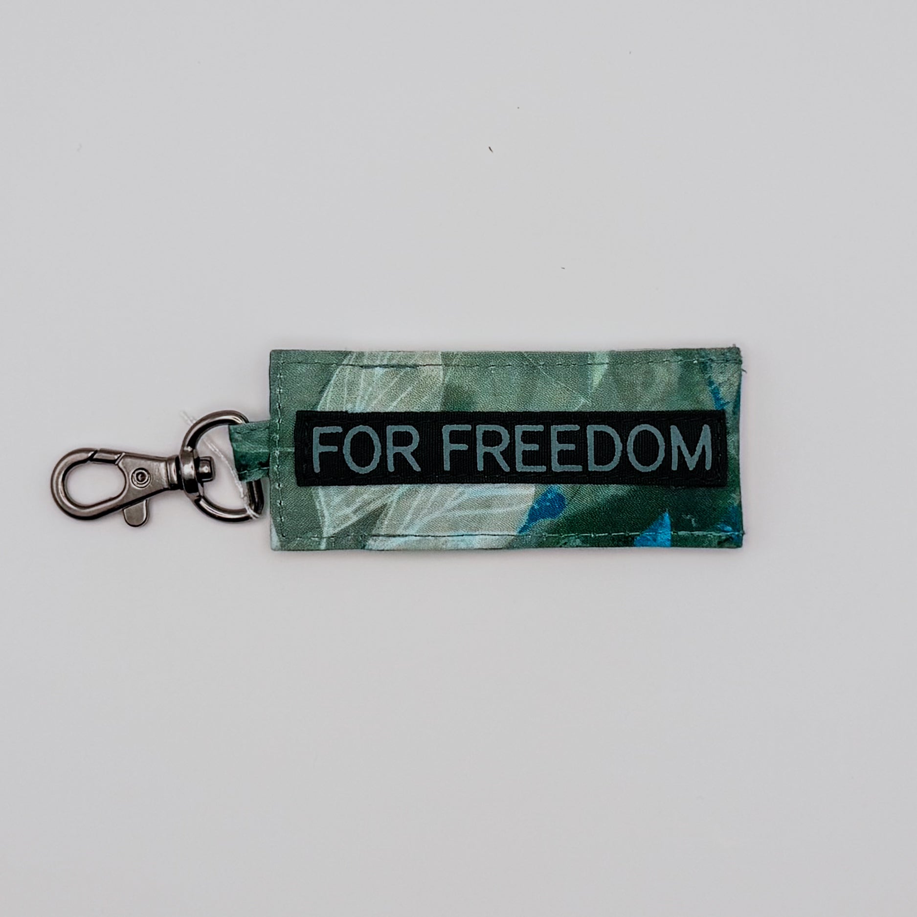 Keychain with 'FOR FREEDOM' text on a green patterned background