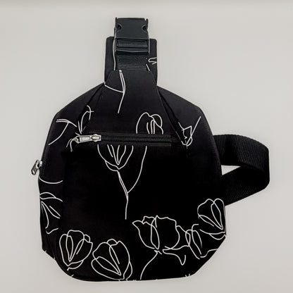 Black sling bag with white floral patterns on a light gray background