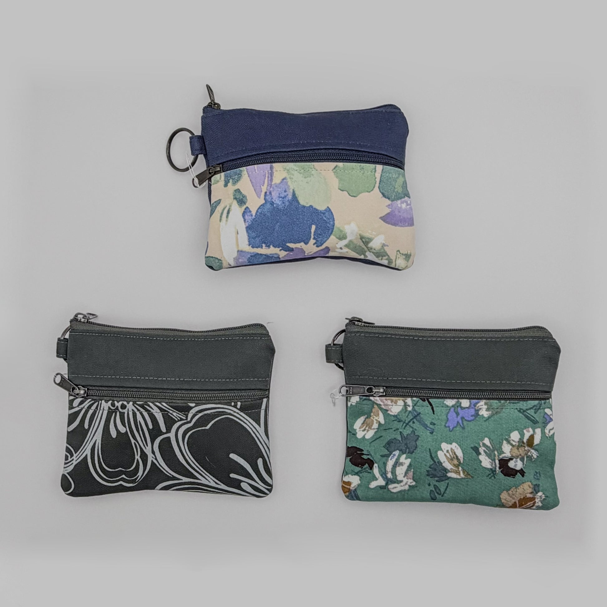 Three fabric pouches with floral and abstract patterns on a gray background