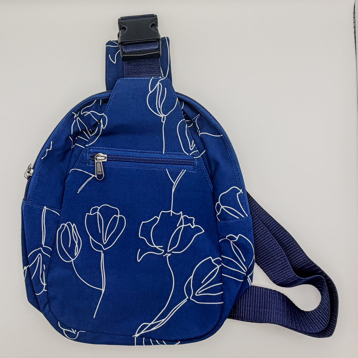 Blue sling bag with floral pattern on a light gray background