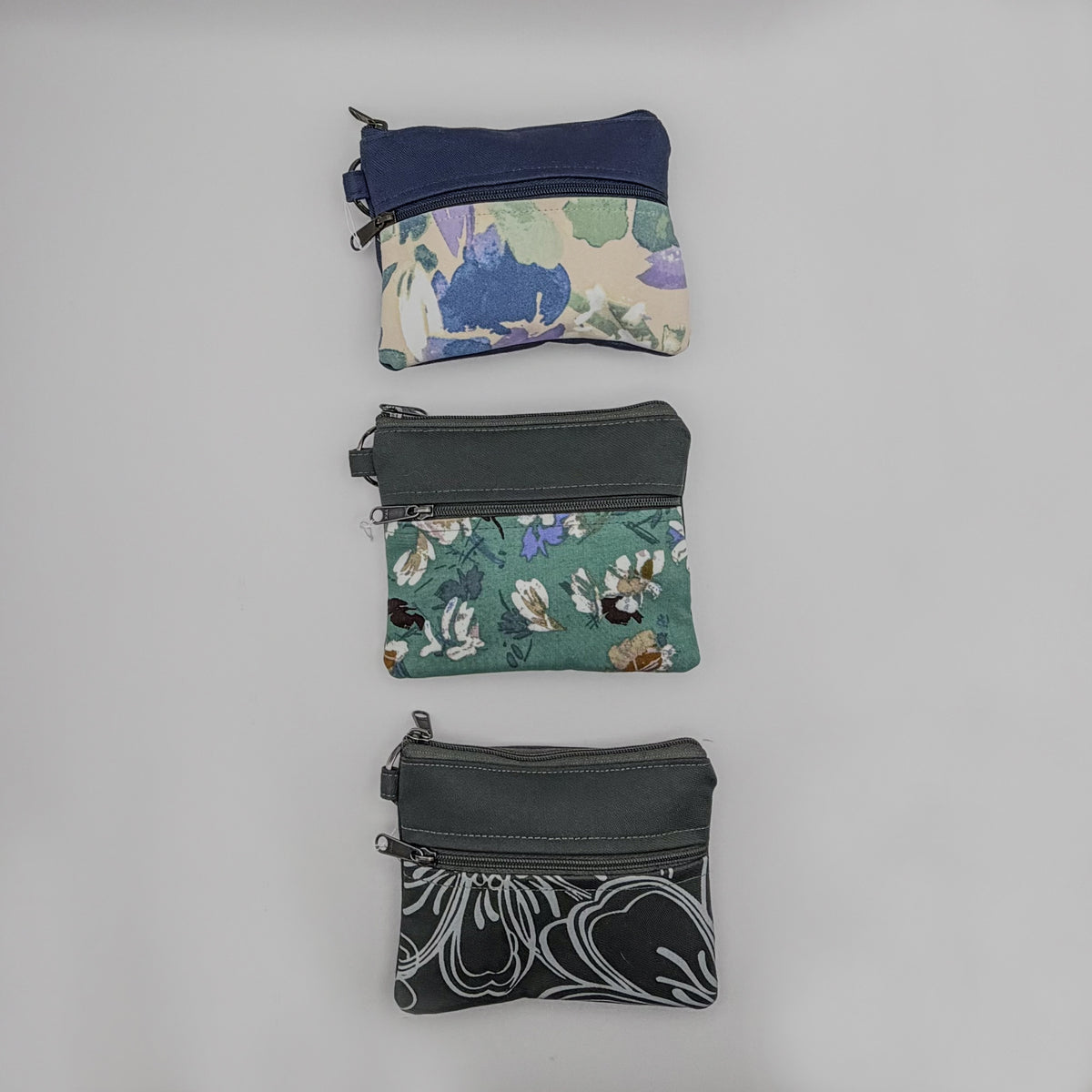 Three small fabric pouches with floral patterns on a gray background